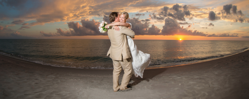 Eine Braut und ein Bräutigam genießen ihre Hochzeit bei Sonnenuntergang am Strand des Tween Waters Island Resort