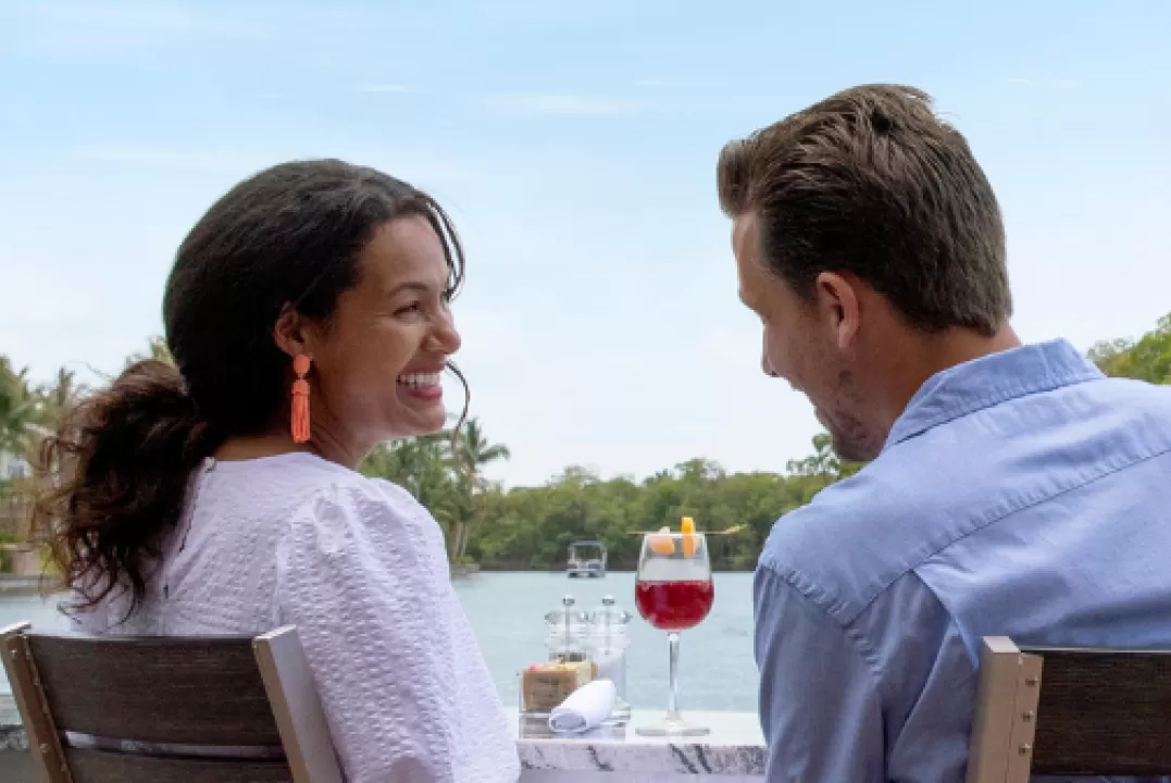 Ein Mann und eine Frau genießen ihr Mittagessen auf einem Kanal in Cape Coral, während ein Boot vorbeifährt