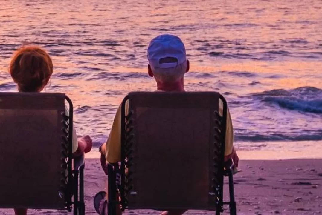 Ein Paar beobachtet den Sonnenuntergang in zwei Liegestühlen am Strand