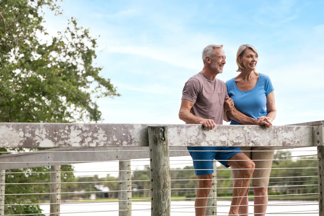 Couple stands on a boardwalk overlooking the water.