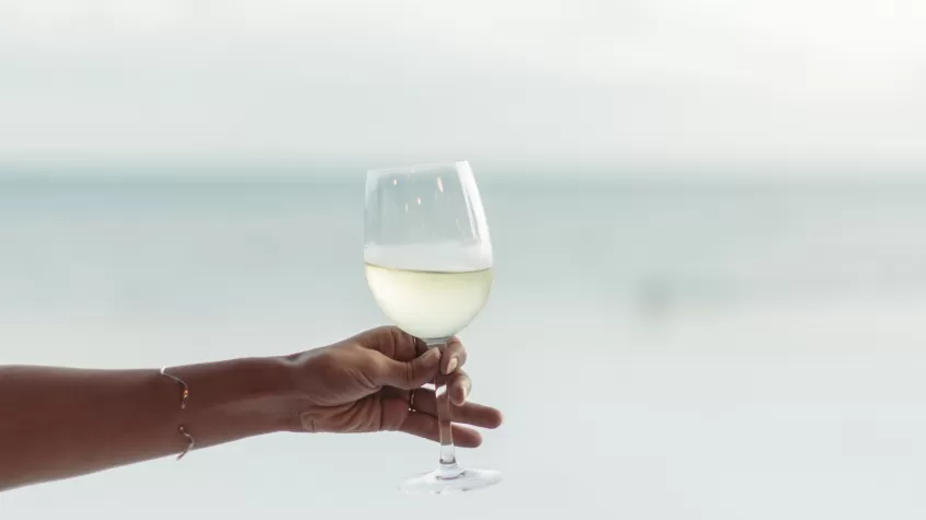 Hand hält Weinglas mit Wasser im Hintergrund