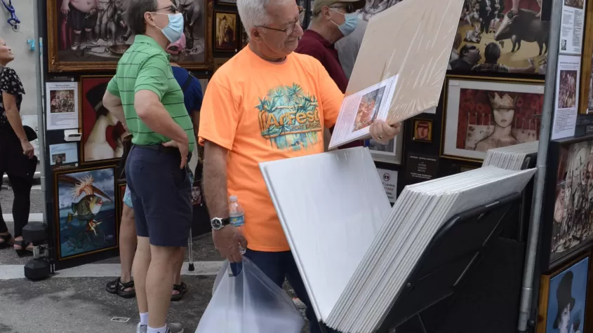 Asistente admirando el trabajo de un artista en ArtFest Fort Myers 2022