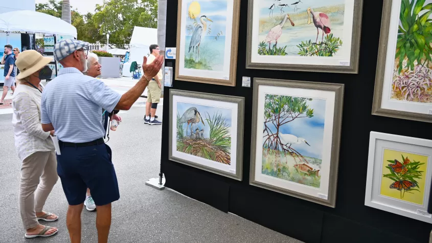 Photo of attendees admiring an artist's work at ArtFest Fort Myers 2022