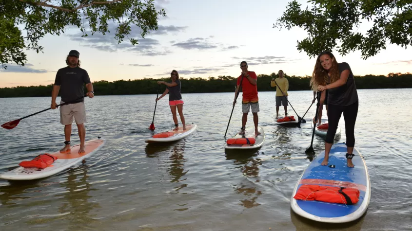 la gente se pone de pie haciendo paddle surf en la vía fluvial