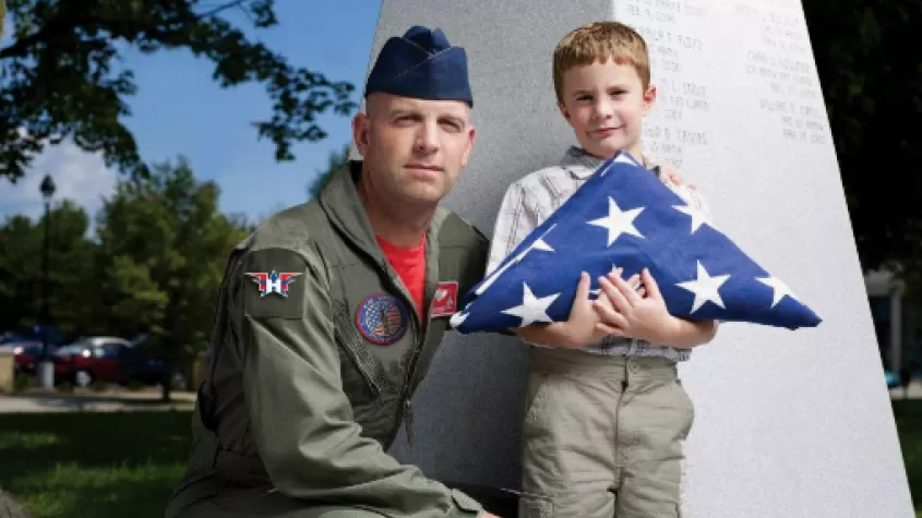 Image of veteran with child holding folded american flag