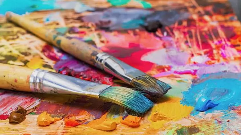 ikmage of paint brushes covered in paint on a board with paint smeared in all different colors