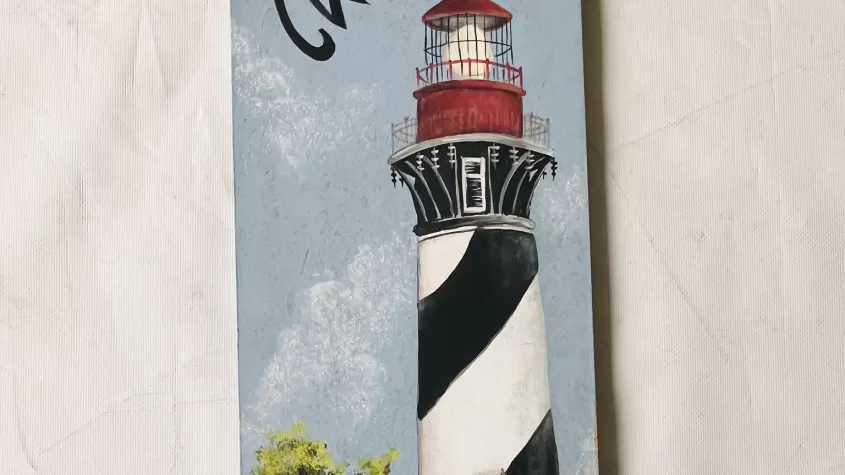 Narrow canvas with a black and white striped light house with a red top and green bushes at the base