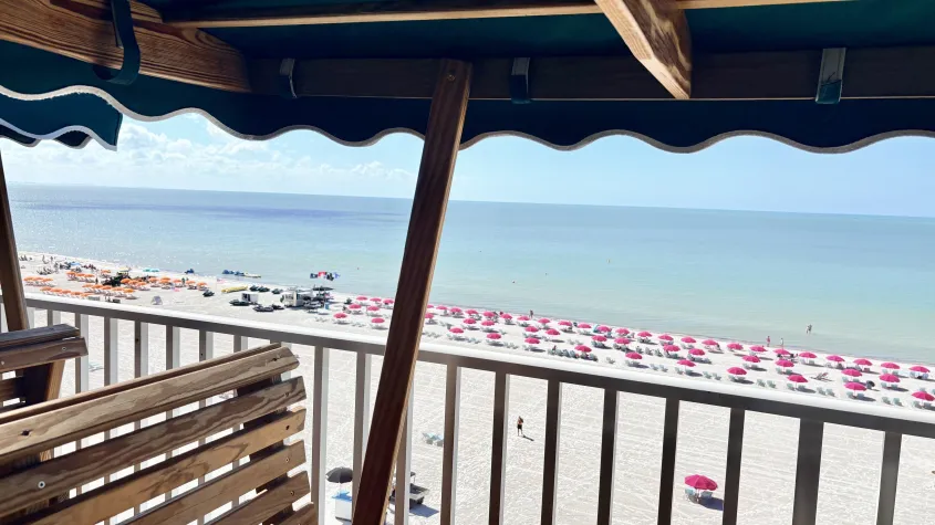 glider chairs overlooking the beach with pink umbrellas and blue water