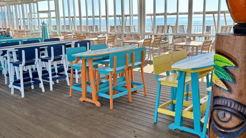 colorful surfboard tables and chairs, wooden floors, tiki hut and parrot statue