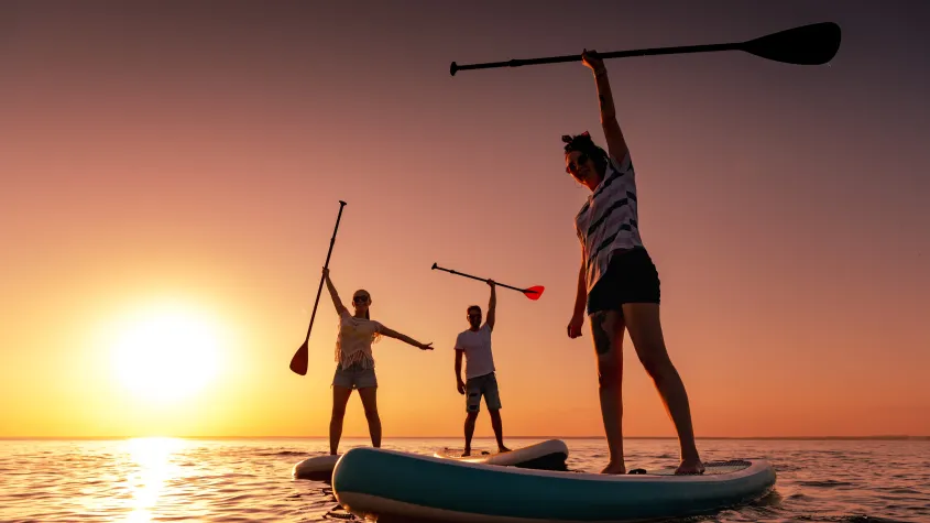 Vacationers enjoying a beach getaway with paddle boards along the shoreline, capturing the relaxed coastal lifestyle of Fort Myers Beach, Florida.