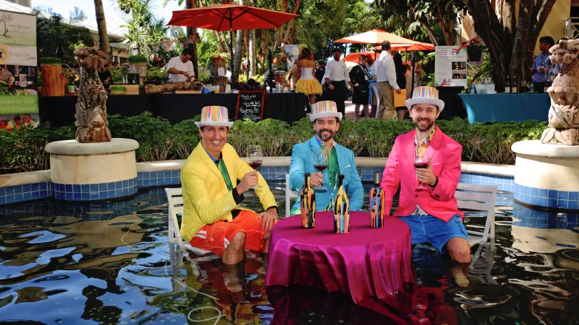 Event photo of men dressed in colorful outfits at a table in a fountain