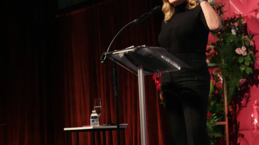 An event photo of a woman speaking on stage.