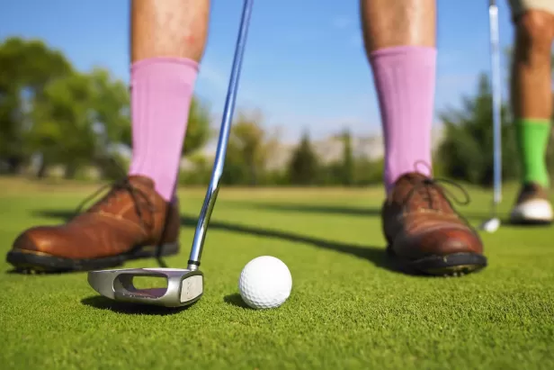 A man is ready to sink his putt.
