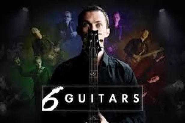Un hombre frente a un micrófono con seis guitarras recortadas detrás de él en una variedad de colores.