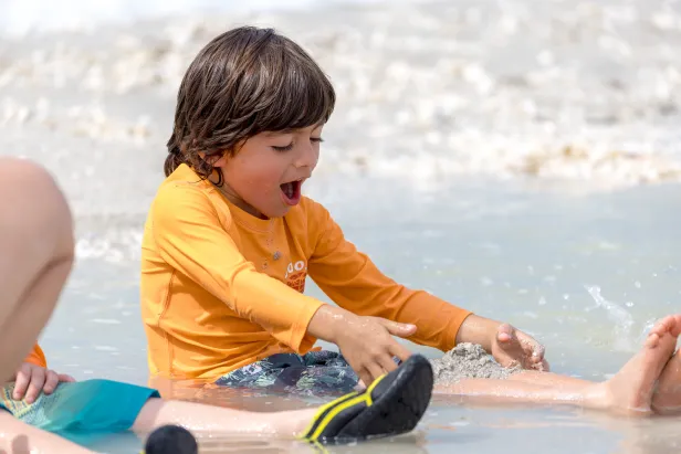 Child playing with shells in the water
