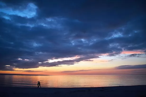 Couple walking along beach at sunset
