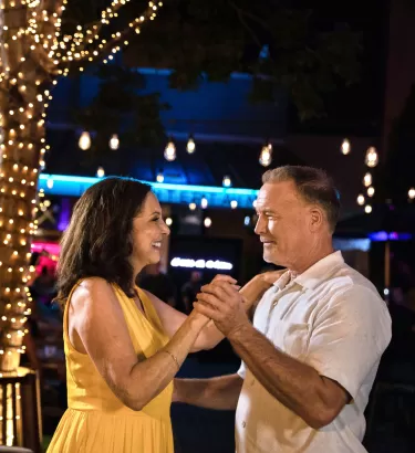 A man and a woman dance at an outdoor bar