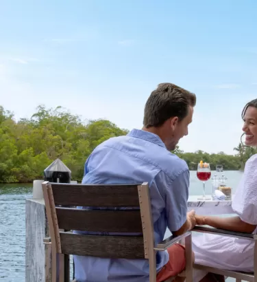 Ein Mann und eine Frau genießen eine Mahlzeit im Freien an einem Tisch neben einem Kanal