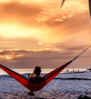 Eine Person, die bei Sonnenuntergang in einer Hängematte liegt
