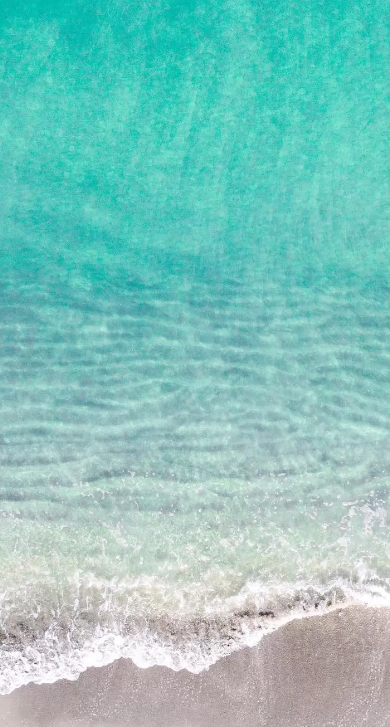 mujer flotando en el agua azul desde la vista aérea sobre la playa