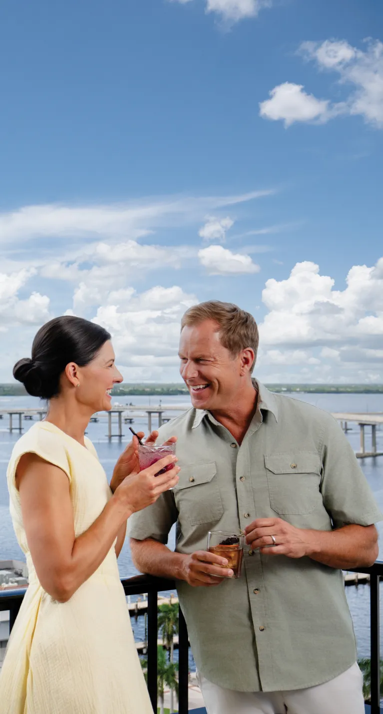 A couple enjoys a drink at a rooftop bar overlooking the river