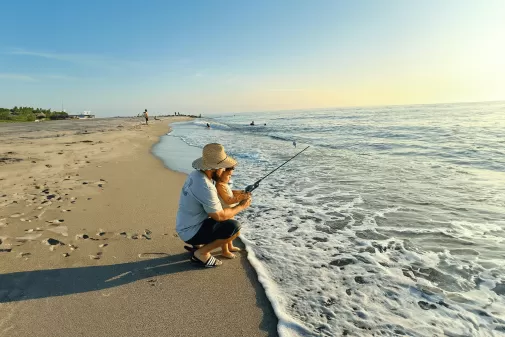 Eine Familie angelt an einem Strand neben dem Meer