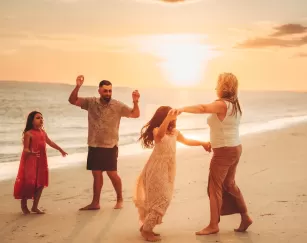 Portrait de famille au coucher du soleil sur la plage dansant
