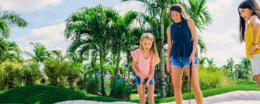 Eine Mutter und ihre beiden Töchter spielen Minigolf