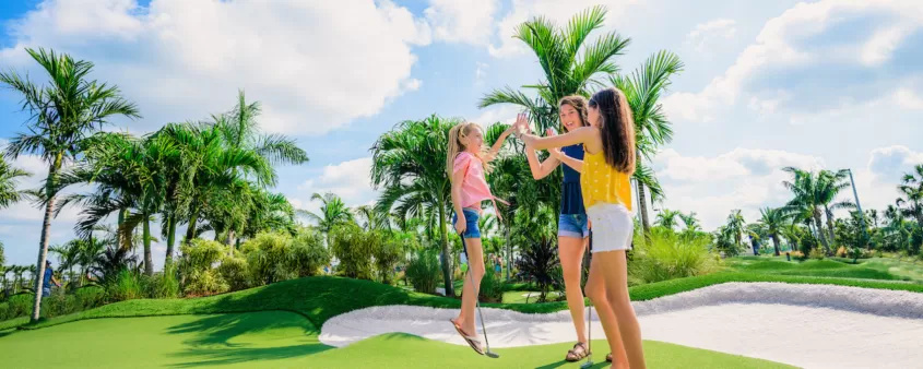 Una madre y sus dos hijas chocan los cinco en el hoyo en un campo de golf popstroke
