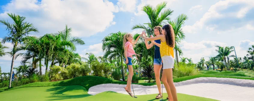 Une mère et ses deux filles font un high-five au trou au cours de putting popstroke