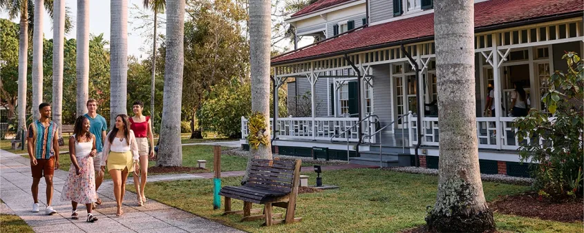 Visitors walk beneath palm trees beside the historic Edison and Ford winter homes in Fort Myers.