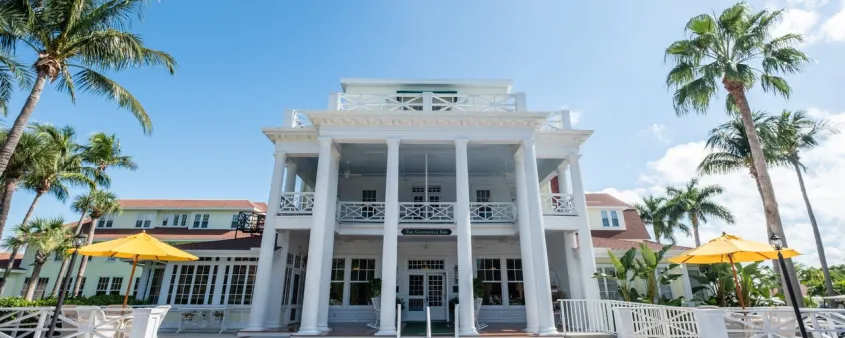 The Gasparilla Inn's columned entrance rises behind palm trees beneath a bright blue sky in Boca Grande.