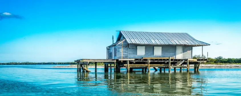 A historic fishing shack stands on stilts above the blue-green waters of Pine Island Sound.