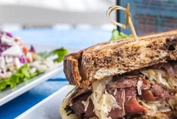 2 sándwiches grandes rellenos con ingredientes se sientan en lugares blancos