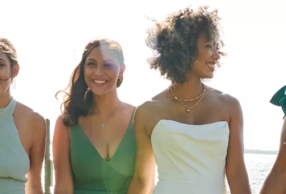 a group of bridesmaids walk along the riverfront