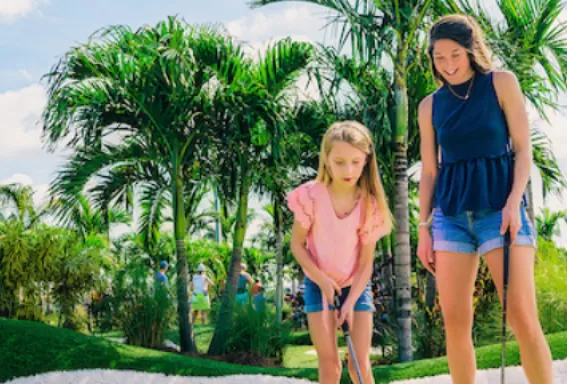 a mom and her 2 daughters play mini golf