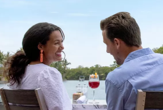 Ein Mann und eine Frau genießen ihr Mittagessen auf einem Kanal in Cape Coral, während ein Boot vorbeifährt