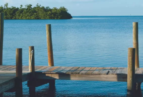 2 people sit and enjoy calm waters from a dock