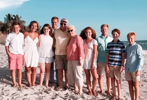 Family standing on top of a sandy beach
