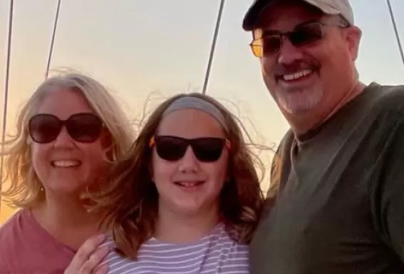 A family smile for the camera aboard a sailboat as the sun sets over the water