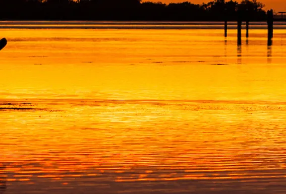 A kayaker paddles off into the sunset