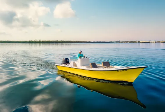 Yellow boat cruising across calm coastal water.