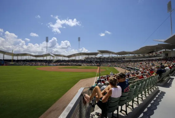 Fans watch a baseball game at JetBlue Park in Fort Myers under a bright blue sky.