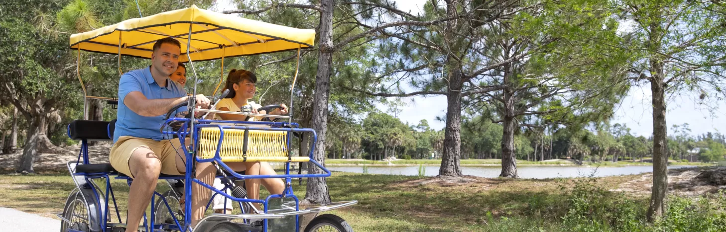 A family of 4 rides a survey bike through Lakes Park