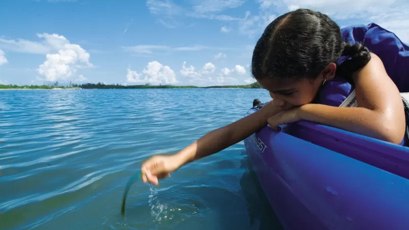 Chica mirando al agua mientras navega en kayak