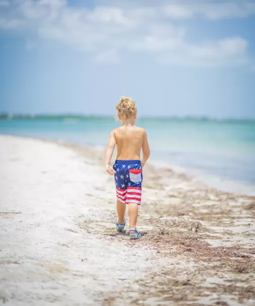 Un garçon sur une plage avec un maillot de bain drapeau américain