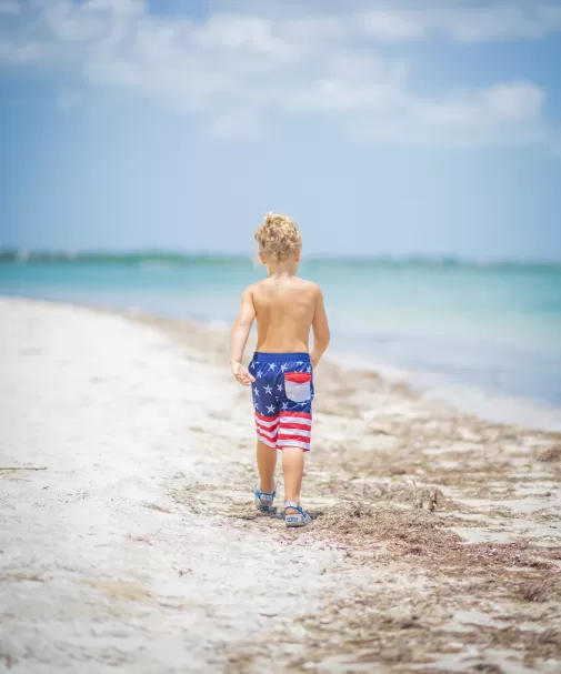 Ein Junge an einem Strand mit Badehose mit amerikanischer Flagge