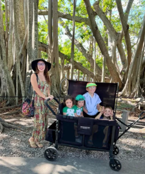 A mom pushes her kids in a wagon through the gardens at Edison and Ford Winter Estates
