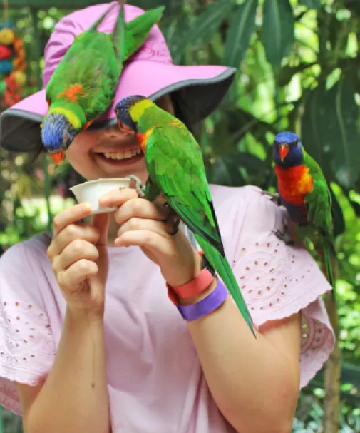 A girl enjoys feeding the parakeets at Wonder Gardens