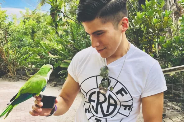 A teen feeds a parakeet at Wonder Gardens